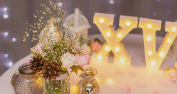 mesa decorada para una boda con flores, luces y letras de XV